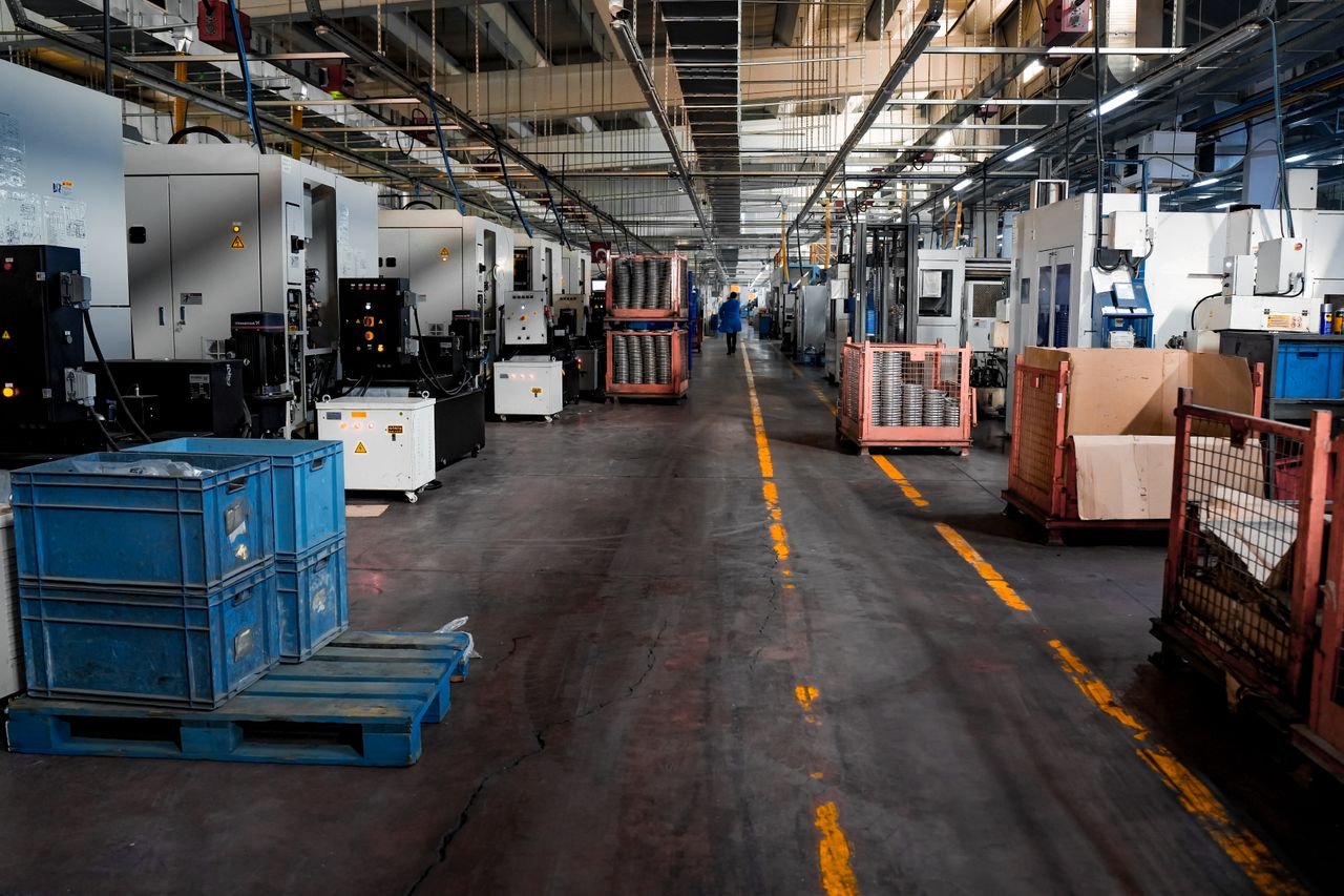 services-06 Vast industrial factory floor with machinery, crates, and structured workstations.