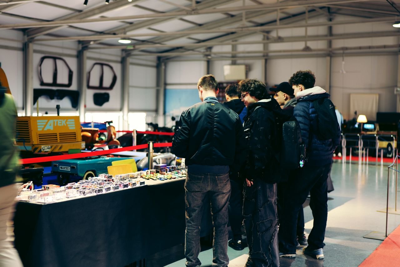 Attendees explore mini car models at an indoor automotive exhibition.