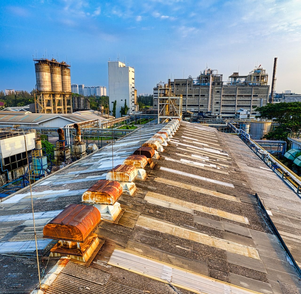 Exterior of aged shabby factory with rusty industrial buildings and mechanisms with pipes in town
