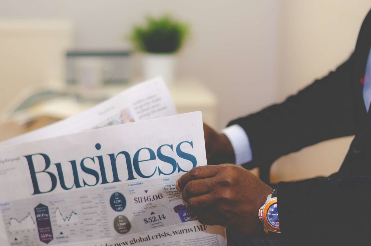 home-hero Close-up of a businessman reading a newspaper indoors, focusing on business headlines.